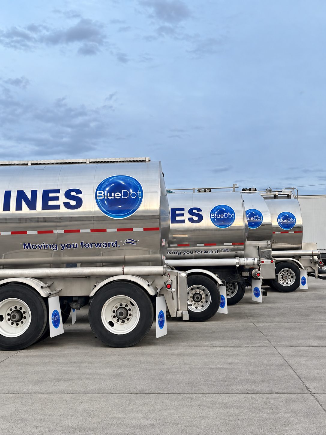 Row of polished stainless Blue Dot tank trailers with the Moving you forward slogan